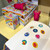 A lifestyle image of a House Of Marbles Rainbow Sticker Stamper in use on notebook.