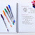 A lifestyle image of Sakura Gelly Roll Classic Gel Pens on a notebook.