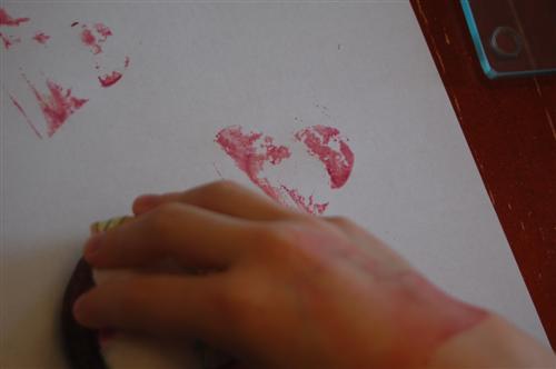Child stamping paper with beet tattoo